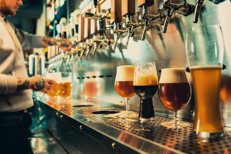 A bartender pouring at a row of taps beside filled glasses