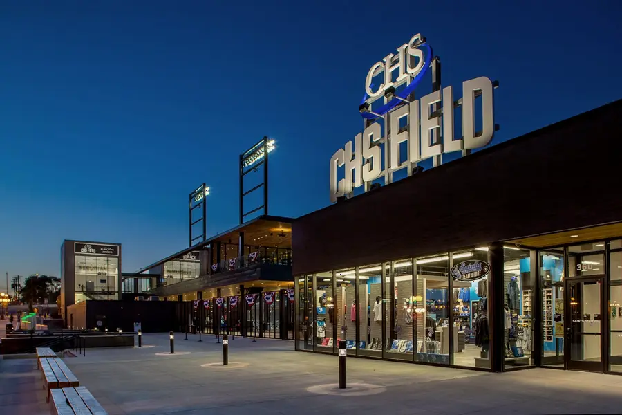 Lit ground-floor storefronts along CHS Field at dusk