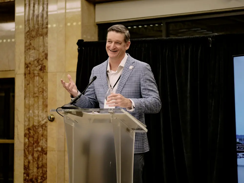 Jamie Rand speaking at a podium at the relighting of the “1st” sign